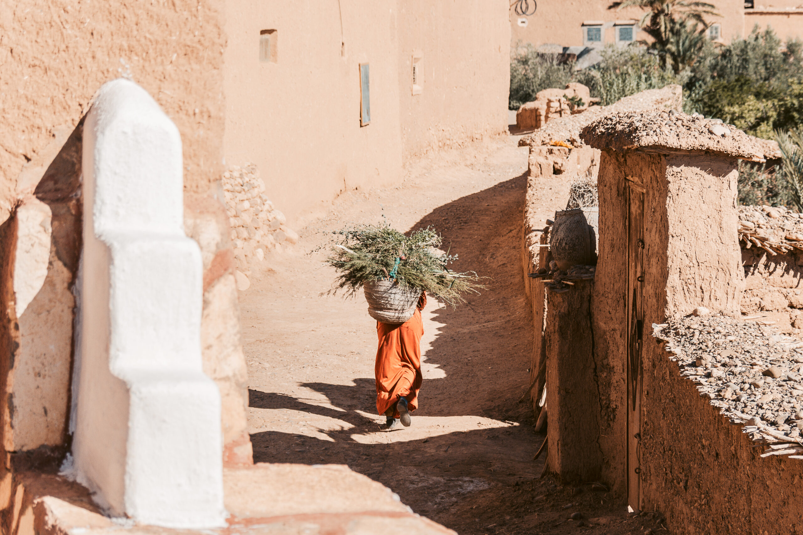 Blick auf eine Person mit Heu auf dem Rücken in der Stadtgasse von Marokko - offlinepleasure.at